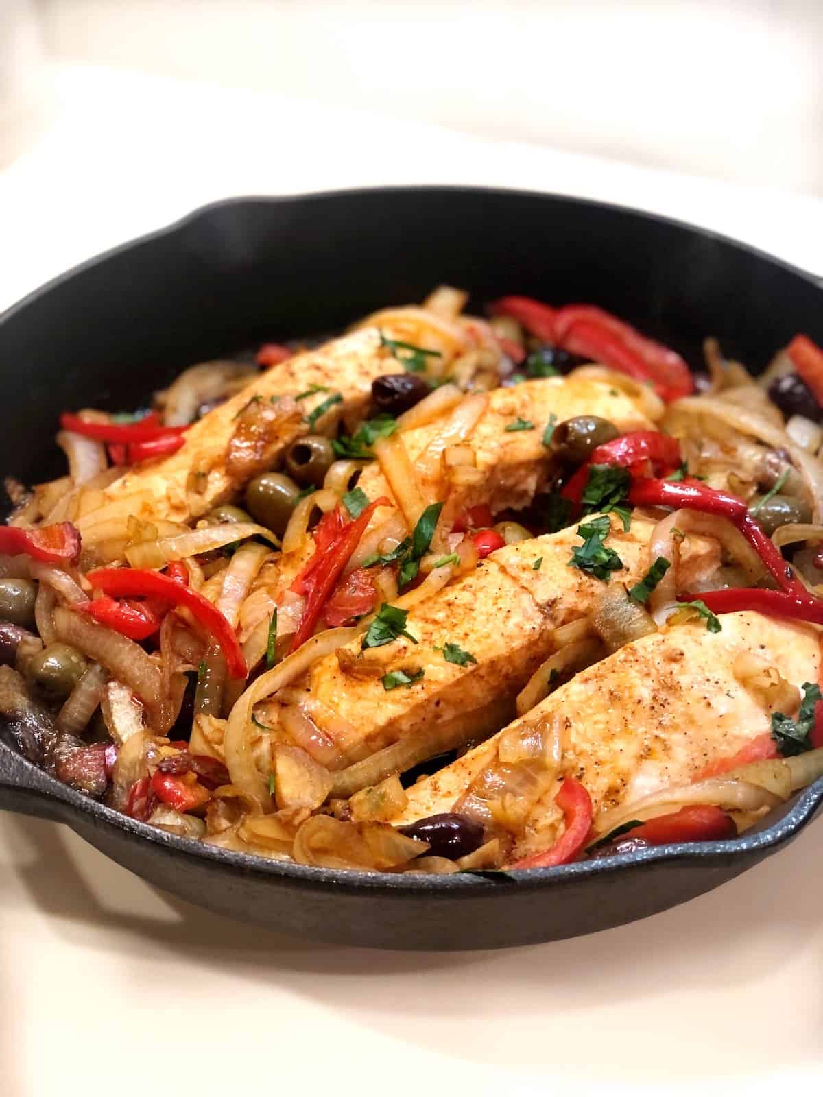 A skillet with Mediterranean salmon, onions and peppers.