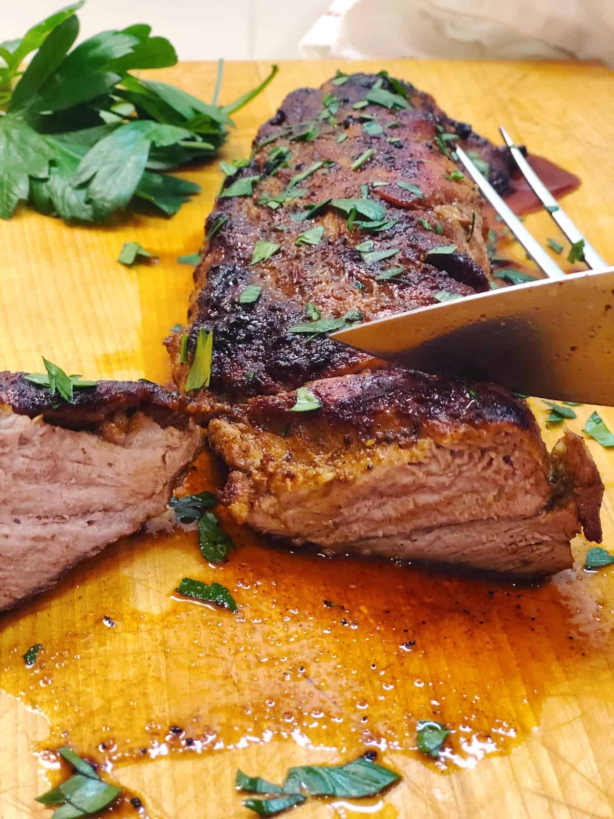 A piece of pork tenderloin on a cutting board with a knife.