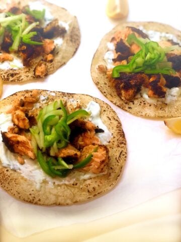 Blackened salmon tacos with yogurt sauce and lemon wedges.