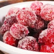 candied cranberries in a bowl on a wooden table.