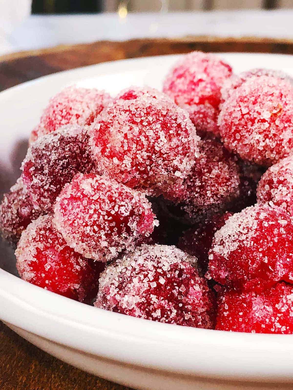 candied cranberries in a bowl on a wooden table.
