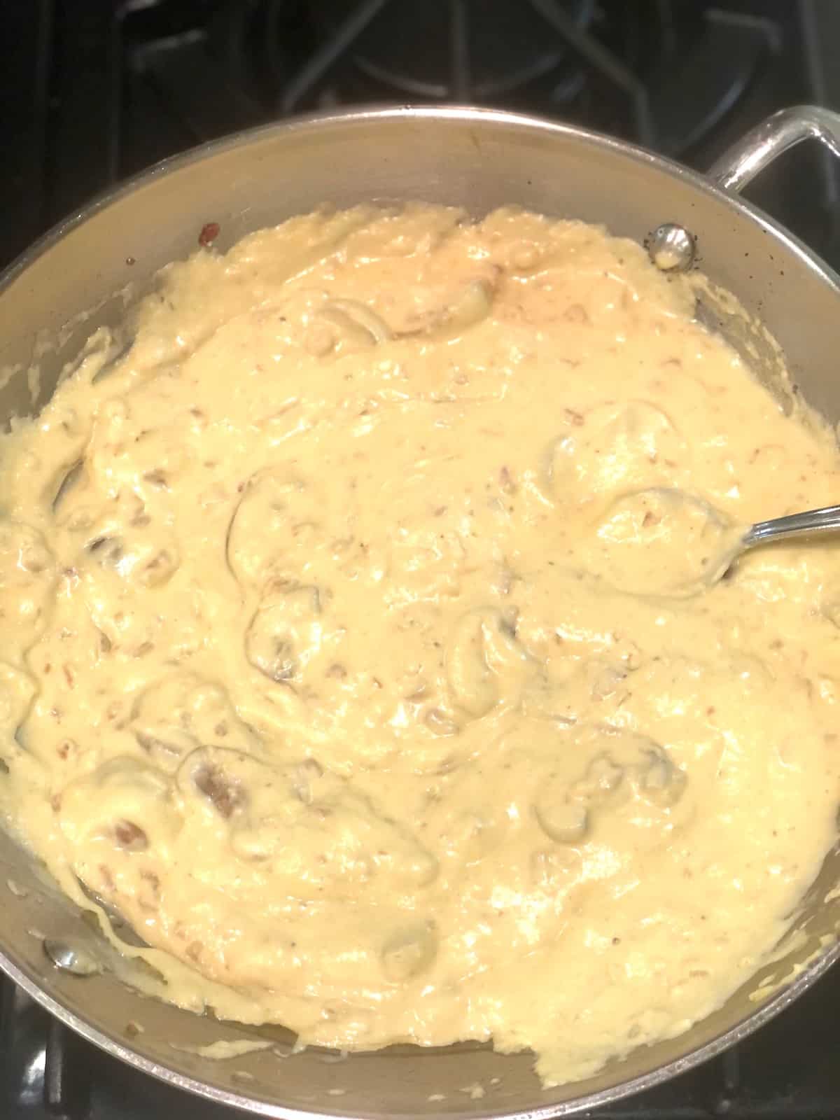 A pan filled with a creamy acorn squash sauce on a stove.