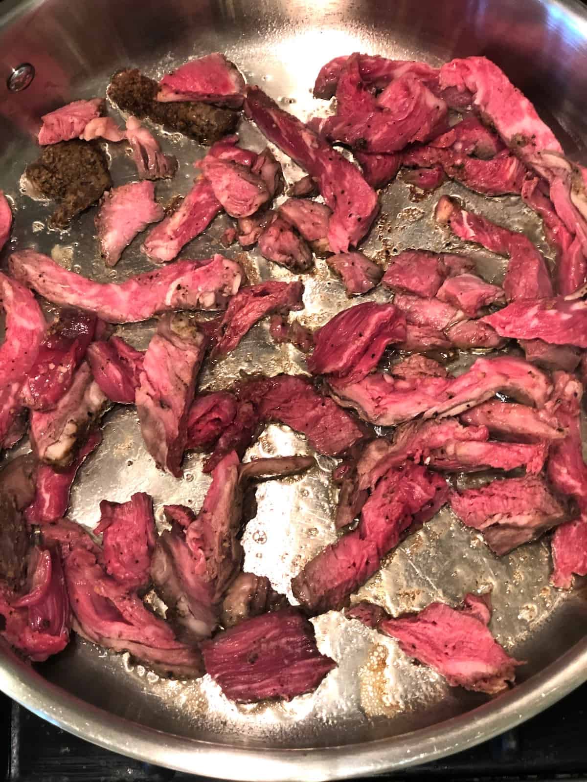 A frying pan with prime rib in it.