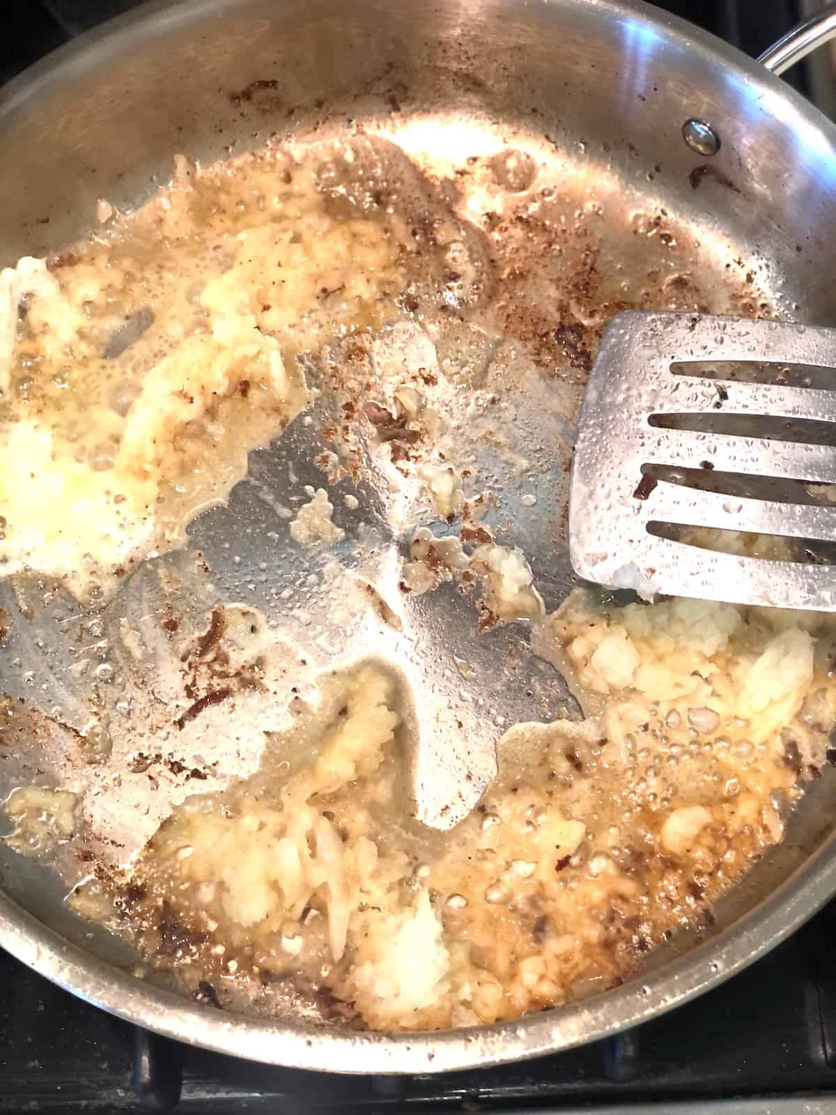 A frying pan with a spoon in it.