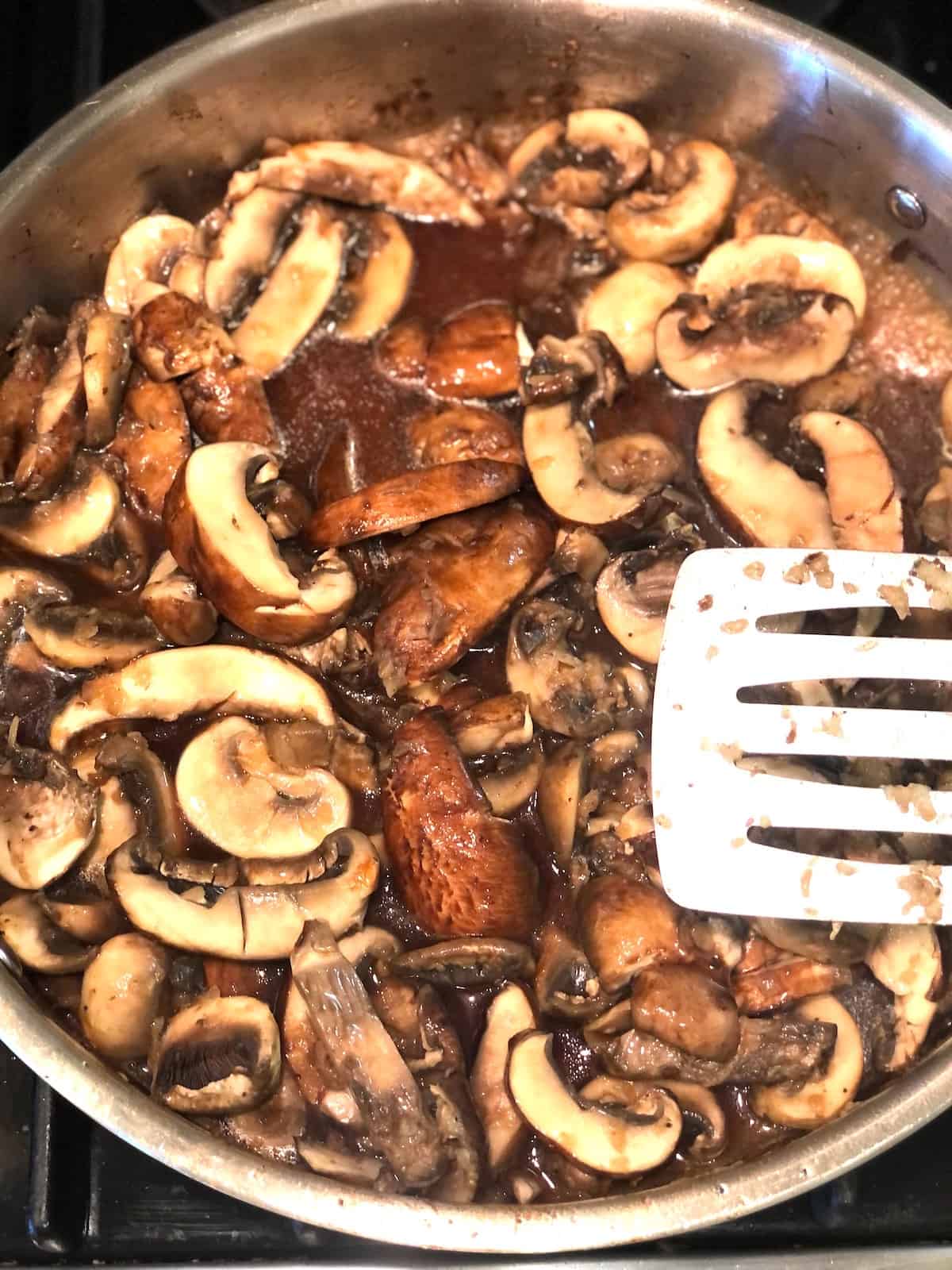 A pan filled with mushrooms and sauce on the stove.
