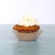 A mini carrot cake cupcake with cream cheese frosting on top.