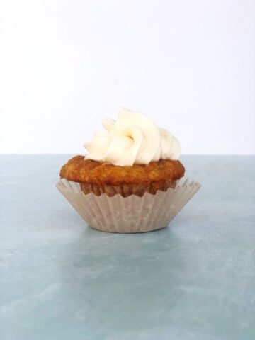A mini carrot cake cupcake with cream cheese frosting on top.