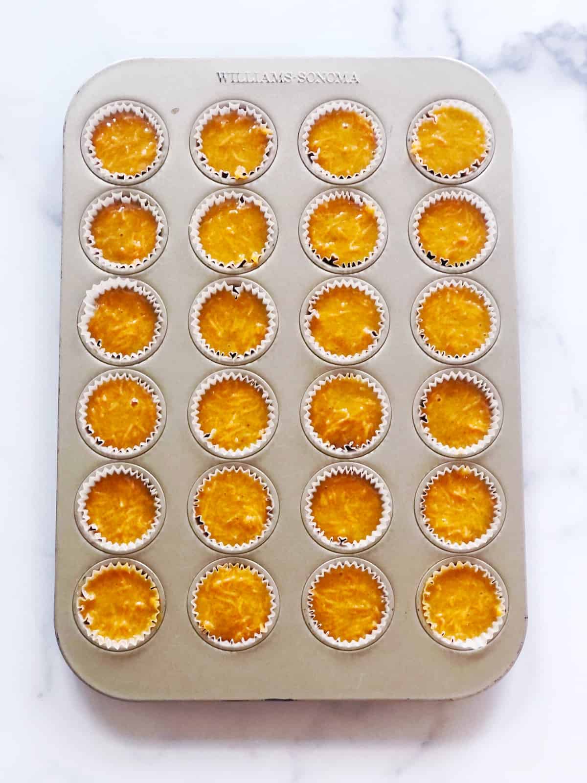 A muffin tin filled with carrot cake batter.