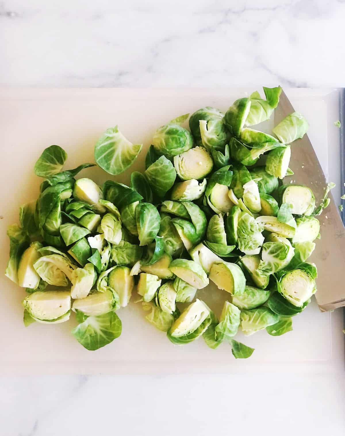 Brussel sprouts on a cutting board with a knife.