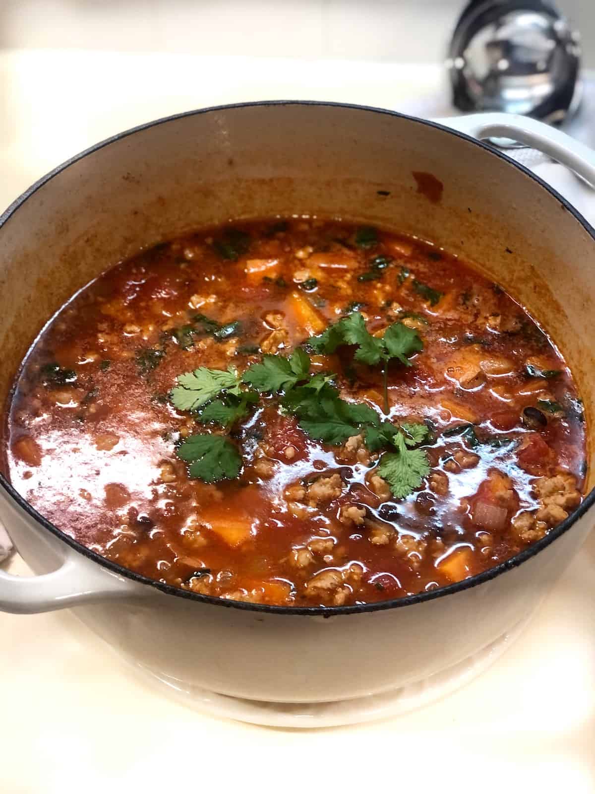 black bean sweet potato soup with sausage in a pot on the stove