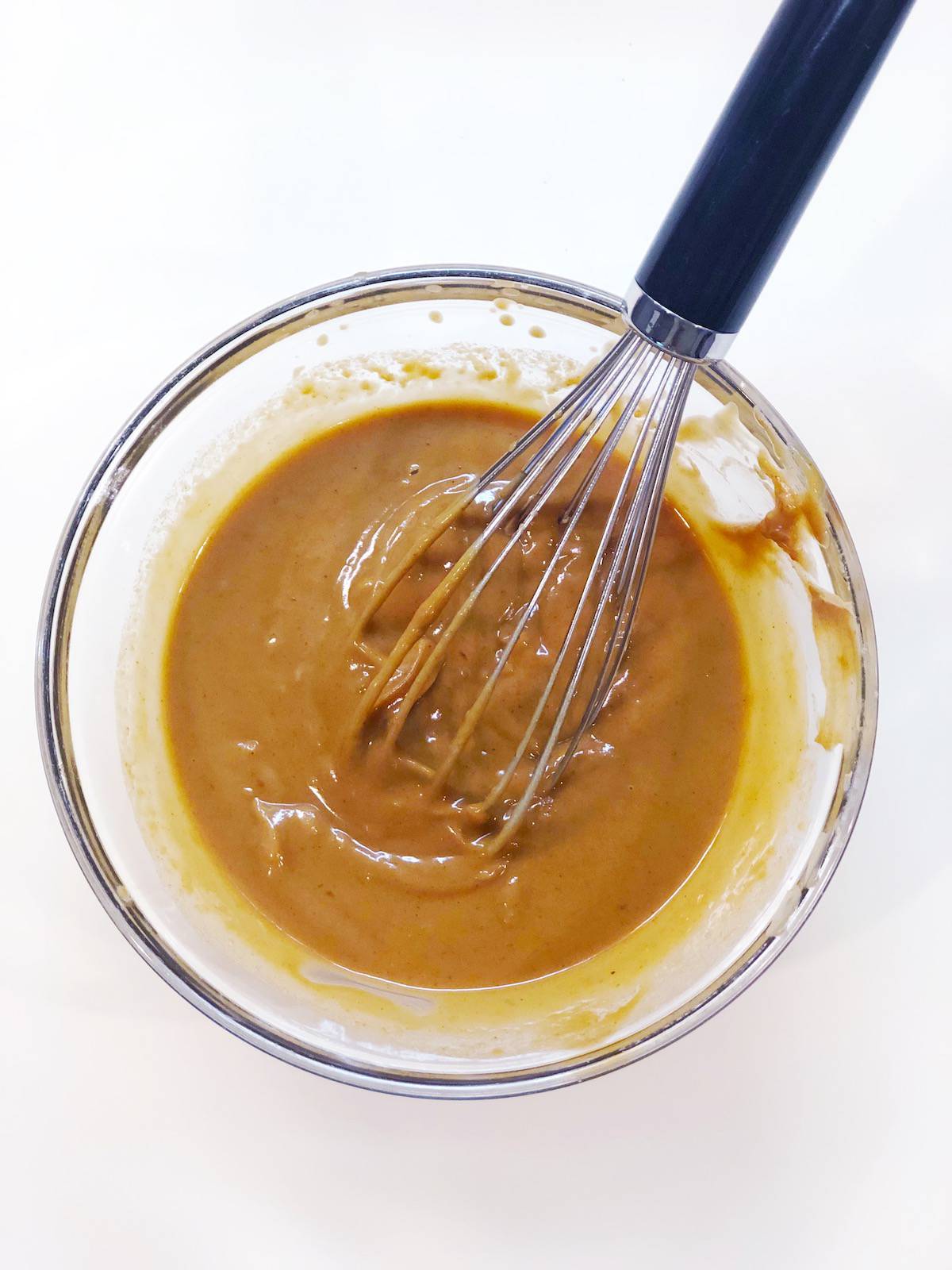 peanut sauce for pasta salad in a small bowl with a whisk.