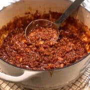 Dutch oven chili in Dutch oven with a ladle.