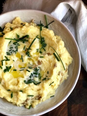 Yukon Gold Mashed Potatoes in a large bowl on a wood board.