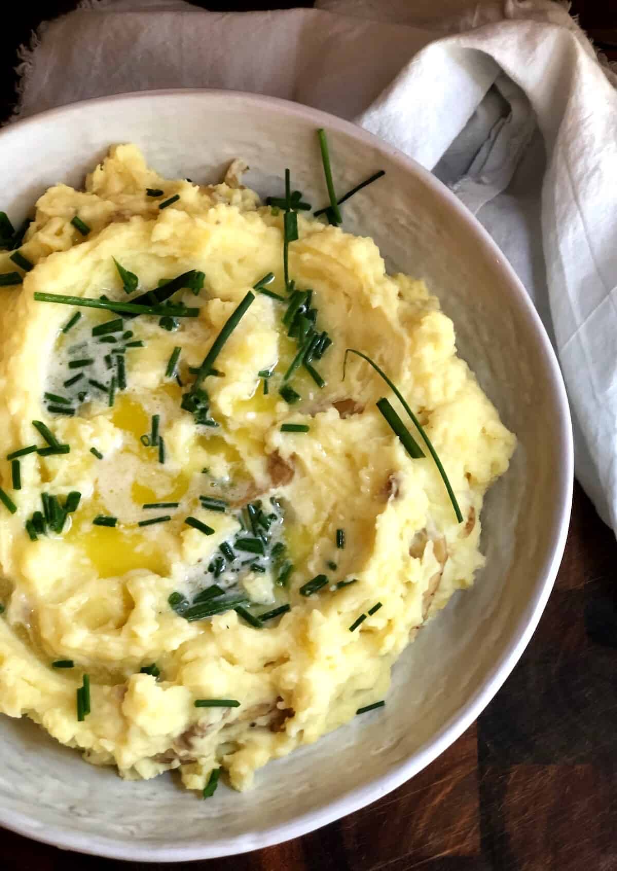 Yukon Gold Mashed Potatoes in a large bowl on a wood board.