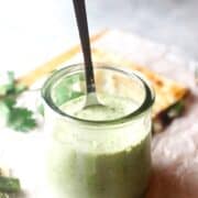 creamy poblano sauce in a container with a spoon.