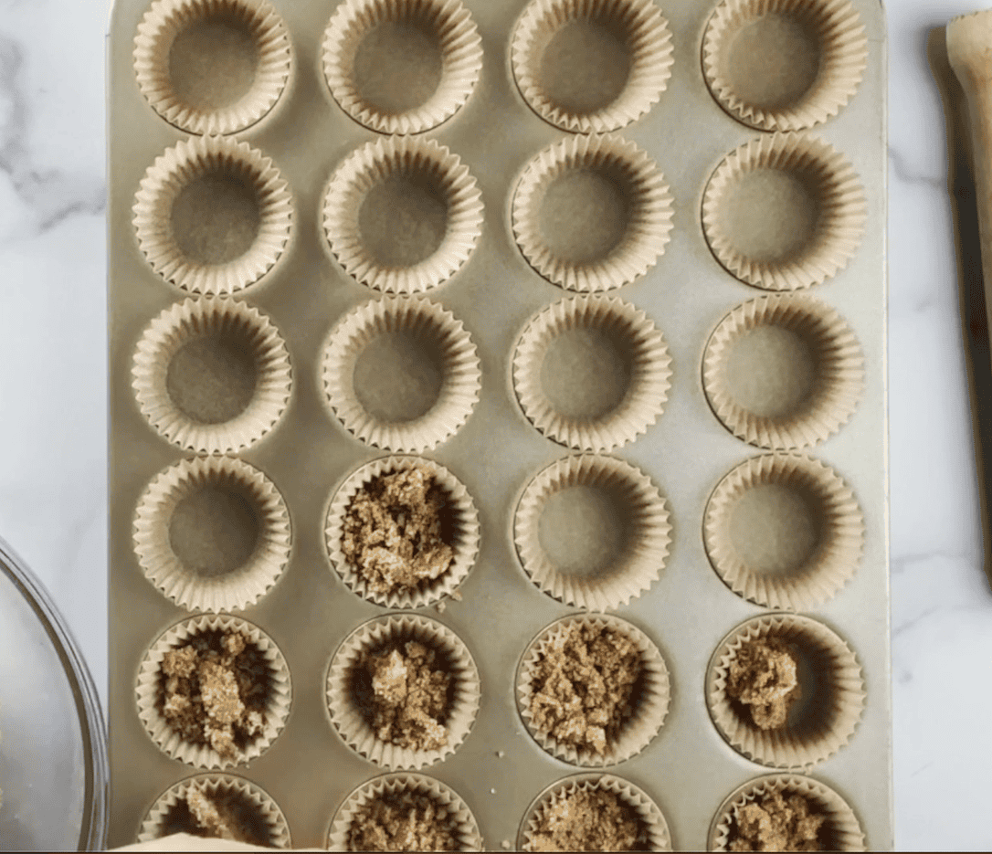 Pressing in Graham cracker crumb mixture into mini muffin pan for the Mini Key Lime Cheesecakes.