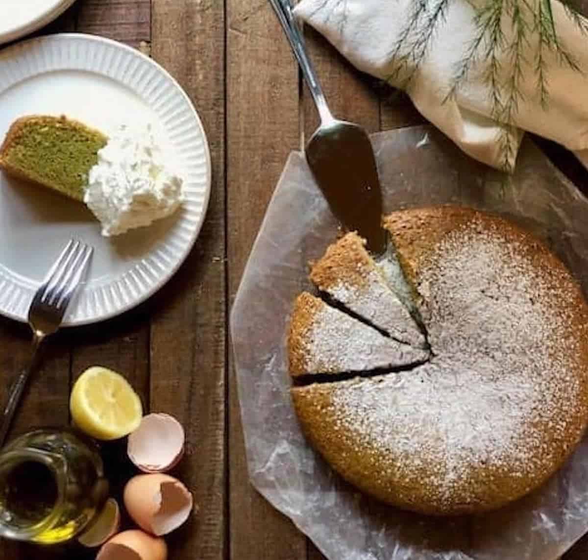 Basil olive oil cake on the counter sliced up with a slice on a plate.