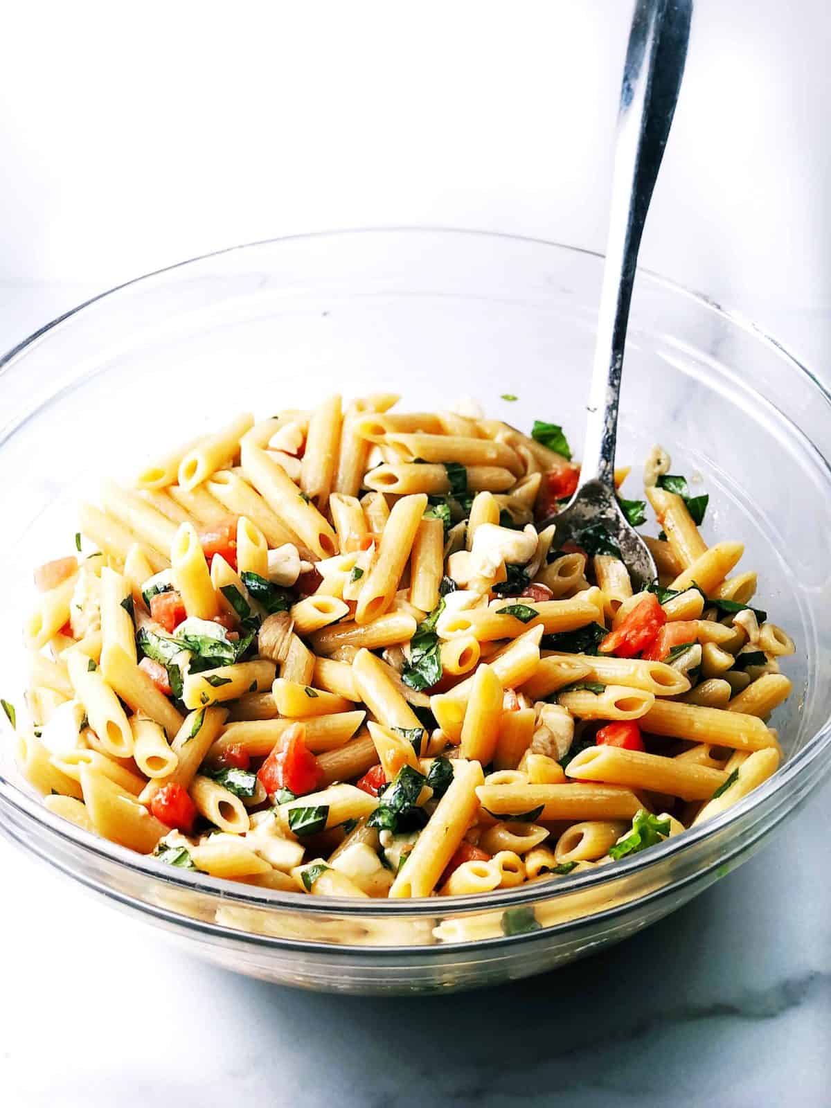 A picture of all of the prepared ingredients in a large glass bowl and mixing it together with a spoon.