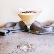 Baileys and vodka martini in a martini glass with shaved chocolate on top sitting on the counter.
