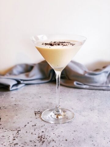 Baileys and vodka martini in a martini glass with shaved chocolate on top sitting on the counter.