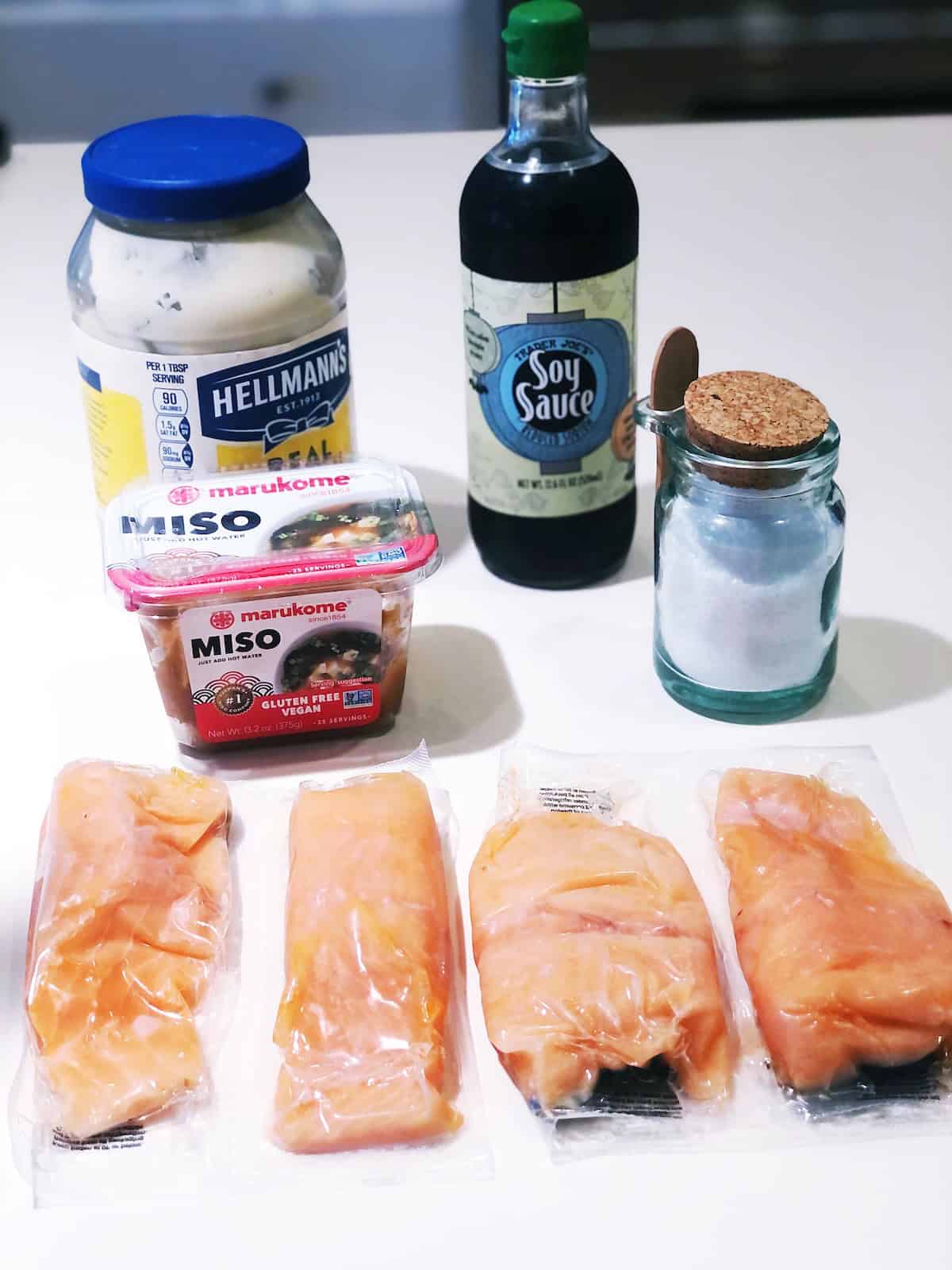 Baked salmon ingredients on the counter including, salmon filets, miso paste, mayonnaise, soy sauce and salt.