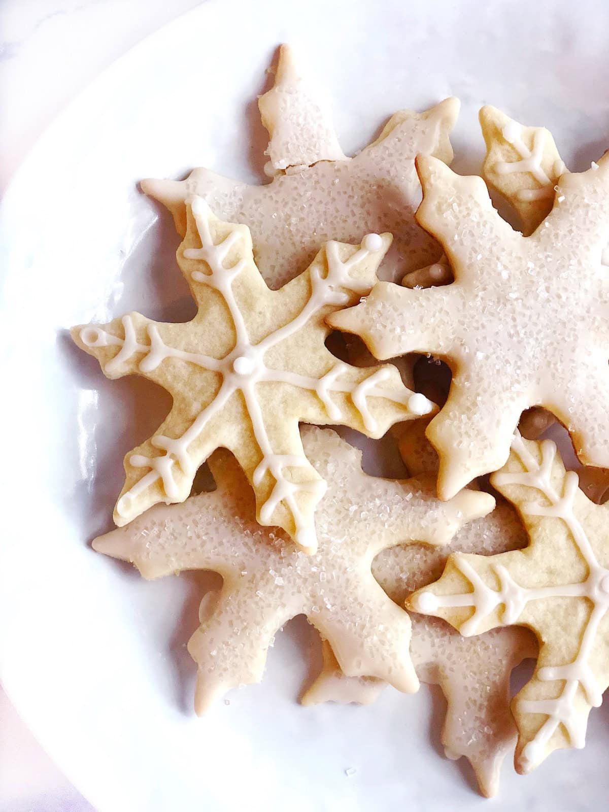 Fully decorated citrus sugar cookies in a snowflake design on a large plate.