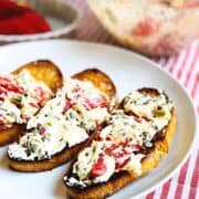 Crostini with goat cheese spread on top on a large plate.