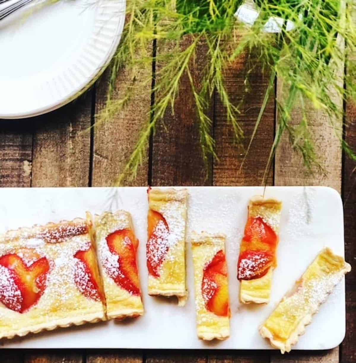 Italian plum tart in a rectangular tart pan on a wood board.
