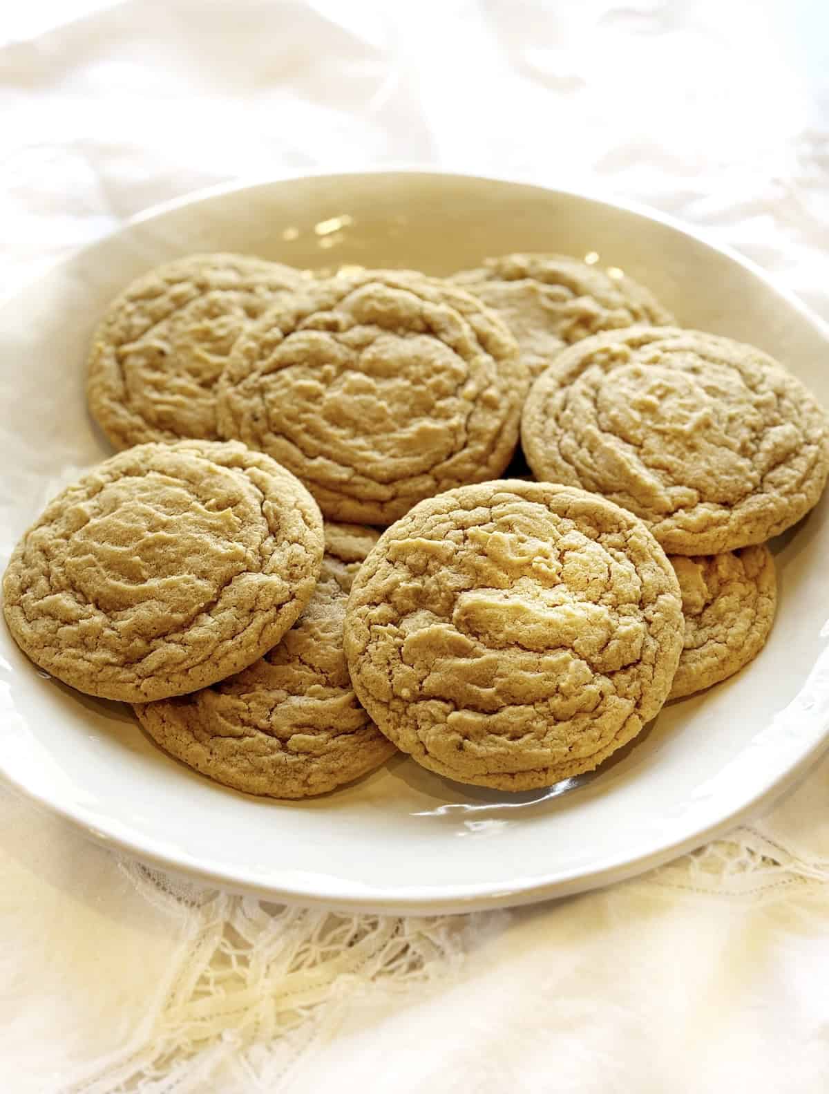 Nutmeg sugar cookies spread out on a white plate.