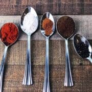 The different spices for the seasoning in individual silver spoons on a table.