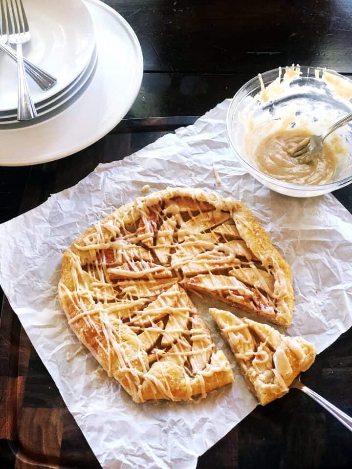 Apple galette with browned butter drizzle over top with a slice cut out.