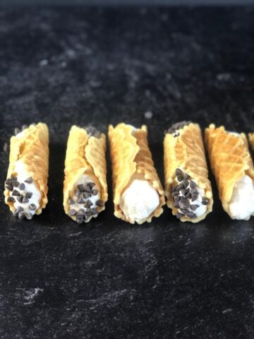 Pizzelle cannoli on a black counter.